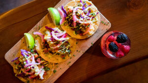 Three open faced soft tacos and a cocktail